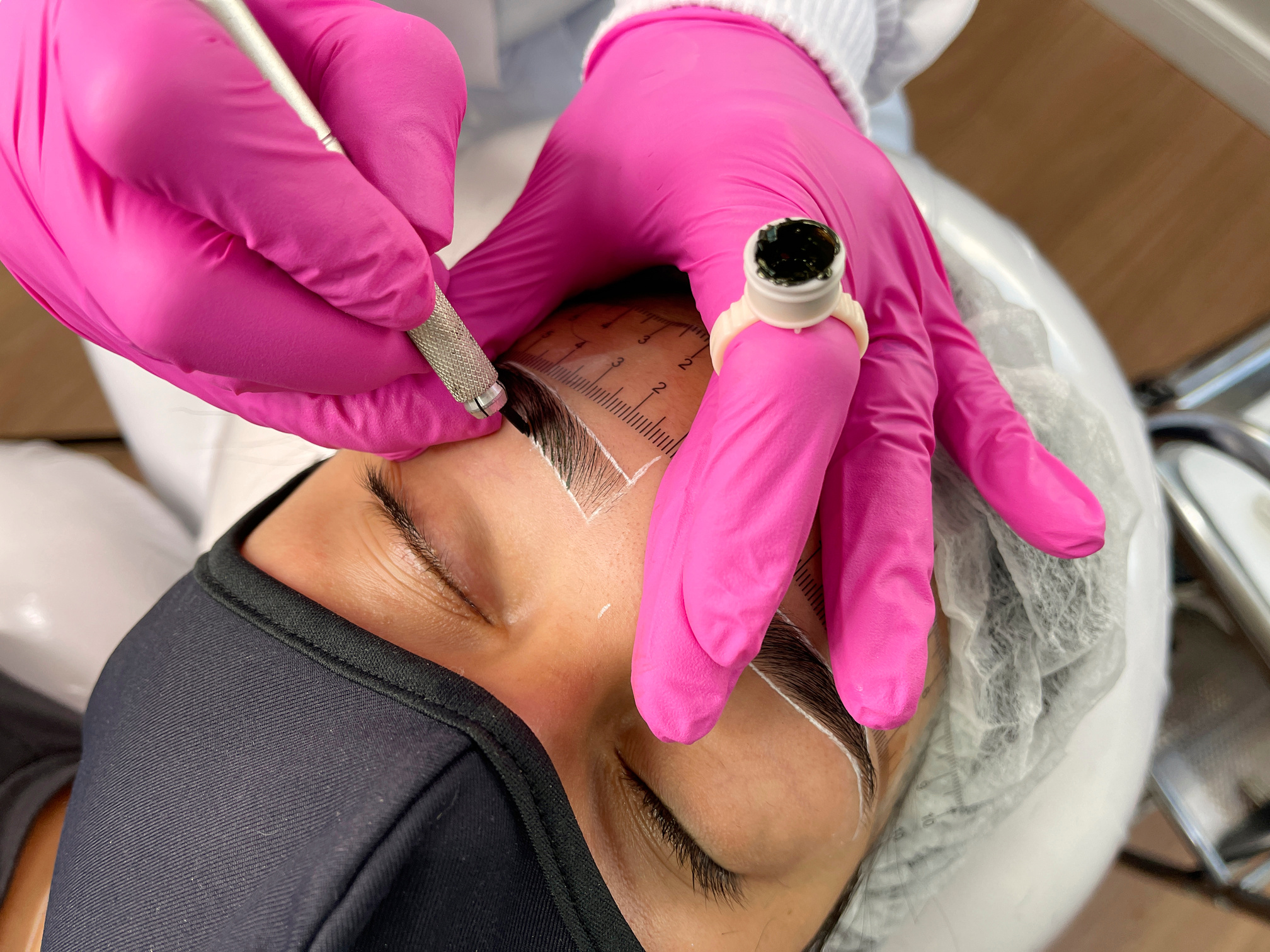 Beautician performing microblading technique in client eyebrow. Thread by thread micropigmentation